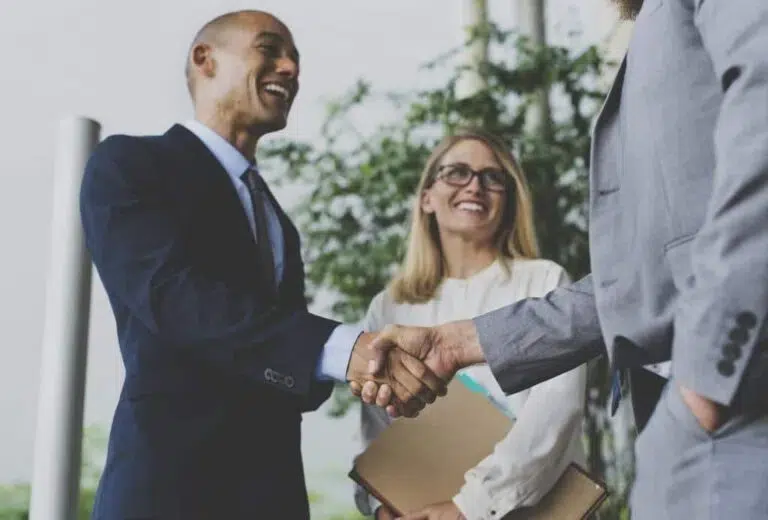 Two professionals shaking hands during a selection and promotion assessment process for key leadership roles.